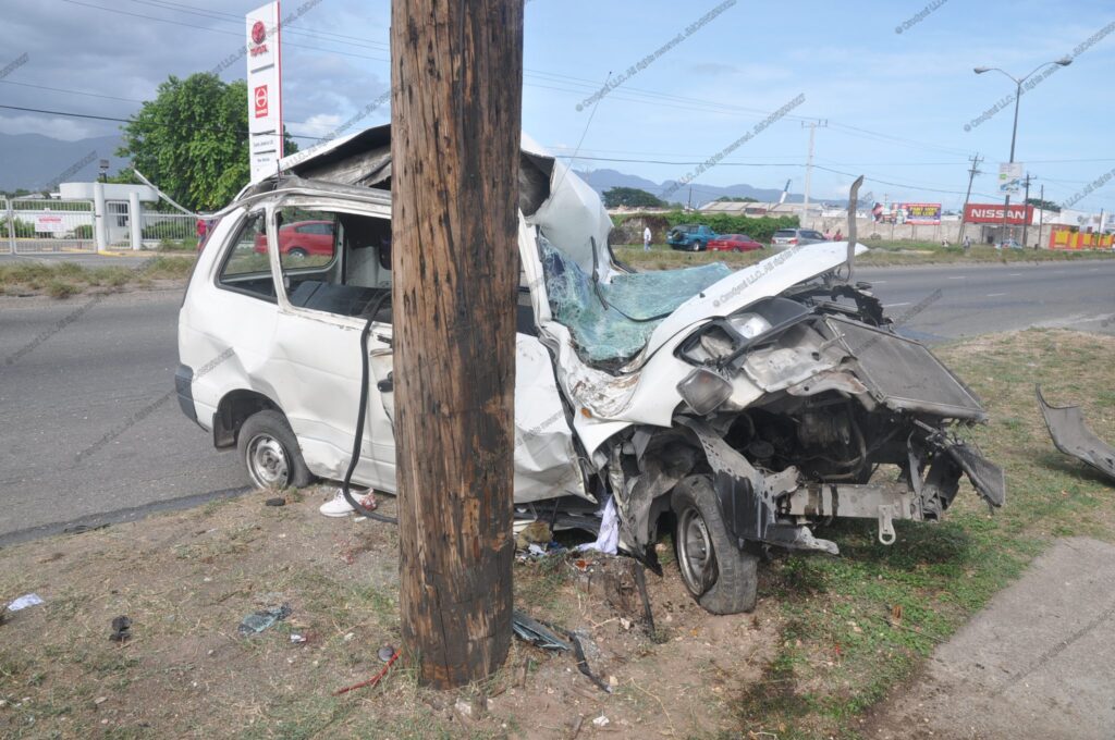 White van wrapped around a wooden utility pole after a severe frontal collision; windshield shattered and front end crushed.