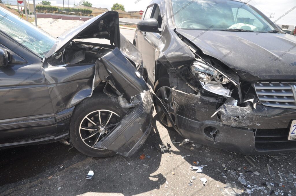 Two vehicles after a front-corner collision at an intersection; crumpled fenders, road debris, right-side airbag deployed.