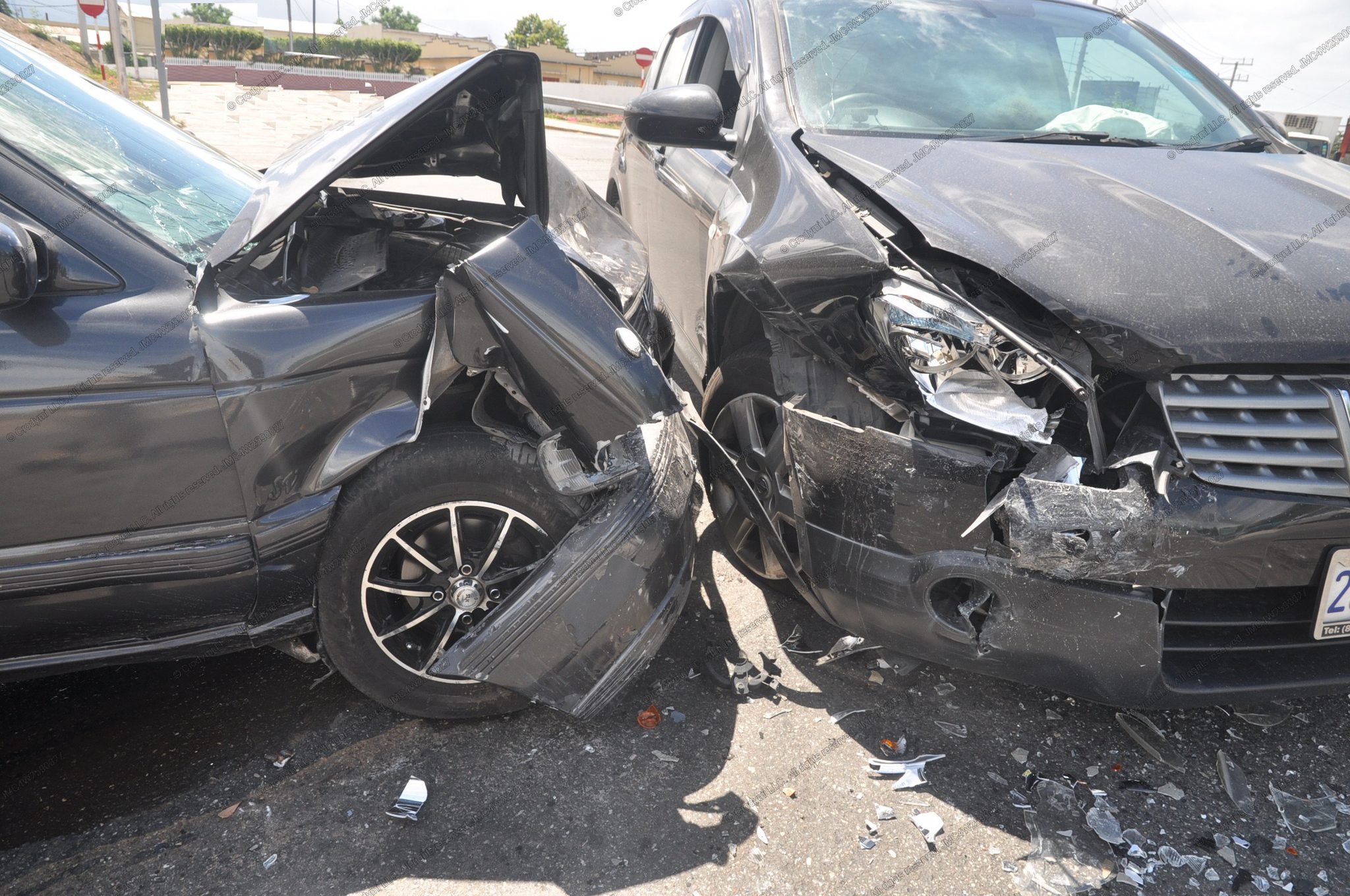 Two vehicles after a front-corner collision at an intersection; crumpled fenders, road debris, right-side airbag deployed.